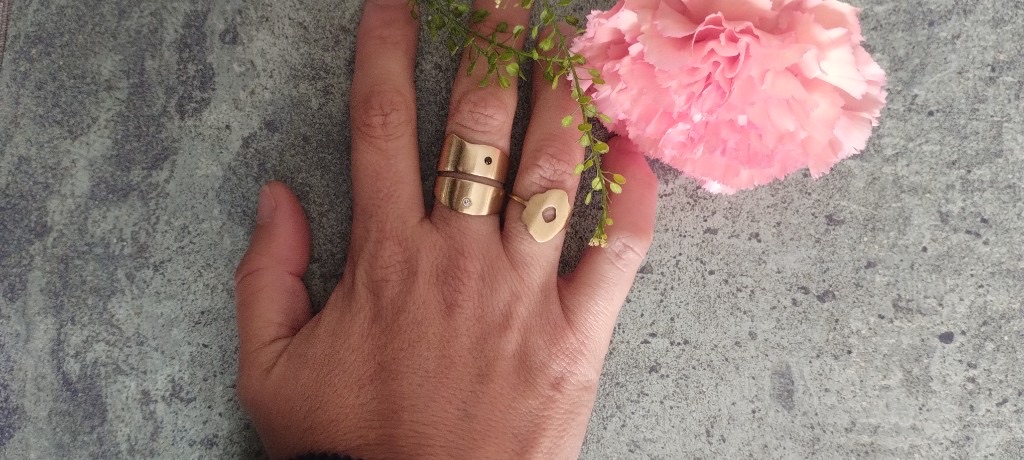 Bague large en laiton portée avec un œillet rose