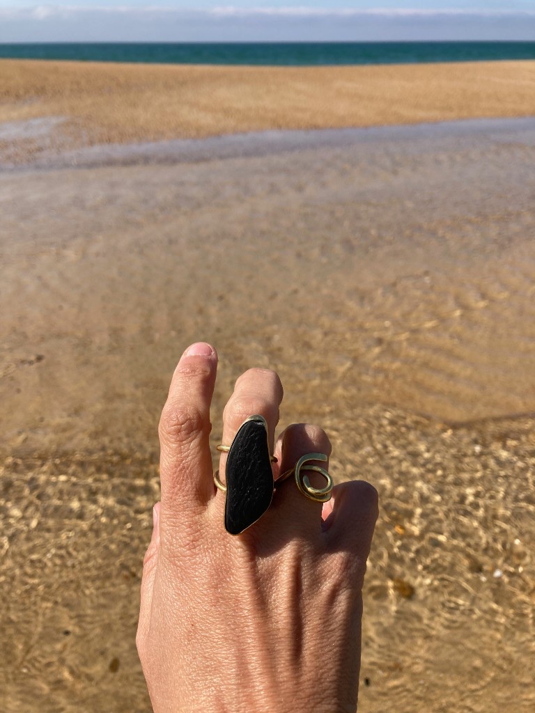 Main portant des bagues sur la plage, mer en arrière-plan